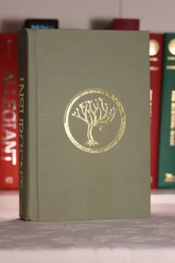 A green hardcover book with golden circle containing a golden tree inside.