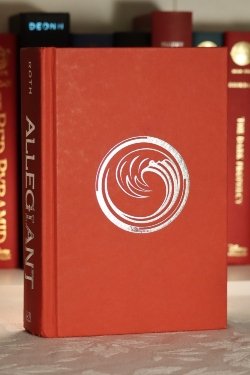 A red hardcover book a silver circle containing a silver wave of water.